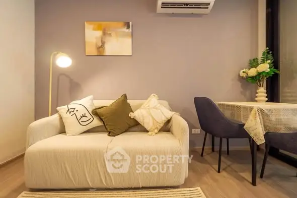 Cozy living room with modern decor and dining area, featuring a stylish sofa and elegant lighting.