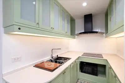 Modern kitchen with green cabinets and sleek appliances in a cozy layout.