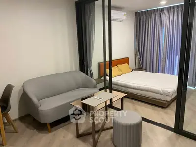 Modern studio apartment with glass partition, cozy sofa, and stylish decor.