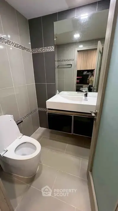 Modern bathroom with sleek design and large mirror in contemporary apartment.