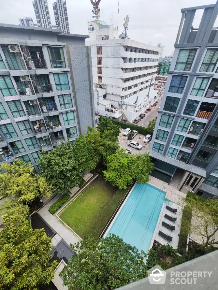 Stunning aerial view of modern apartment complex with lush garden and inviting swimming pool.