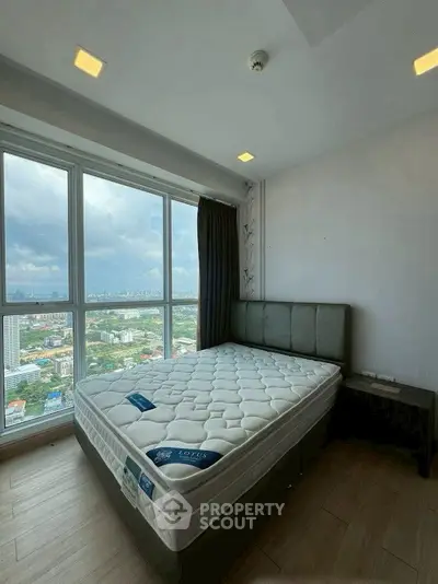 Spacious bedroom with panoramic city view and modern furnishings.