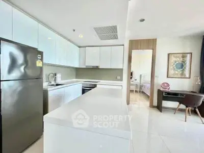 Modern kitchen with sleek white cabinets and open layout, adjacent to a cozy study area.