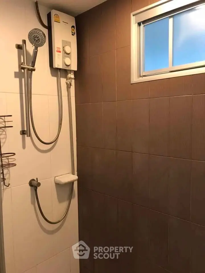 Modern bathroom shower area with water heater and window for natural light.