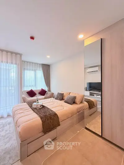Modern bedroom with cozy bed, stylish decor, and natural light from large windows.