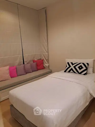 Cozy bedroom with single bed and stylish cushions, perfect for a serene retreat.