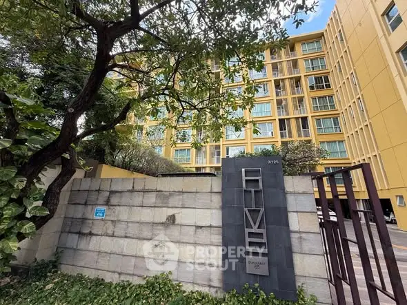 Modern yellow apartment building with lush greenery and secure entrance