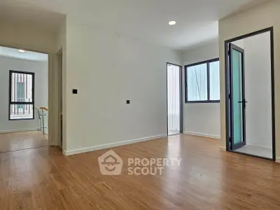 Spacious modern apartment with wooden flooring and large windows for natural light.