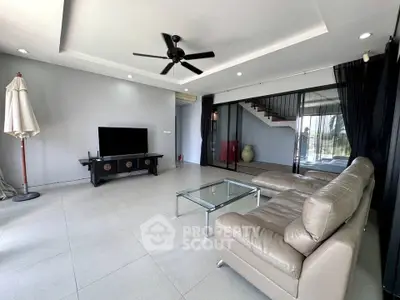 Spacious modern living room with sleek leather sofa and glass coffee table, ideal for relaxation.