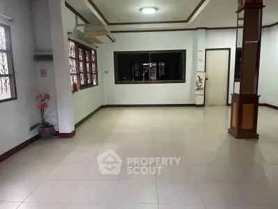 Spacious empty living room with large windows and tiled flooring, perfect for customization.