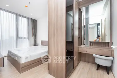 Modern bedroom with wooden furniture and large windows offering natural light.