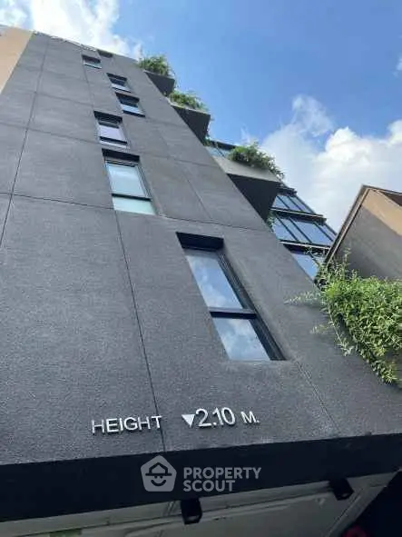 Modern building exterior with sleek design and greenery, showcasing urban architectural elegance.