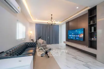 Modern living room with elegant decor, featuring a large TV and stylish furniture.