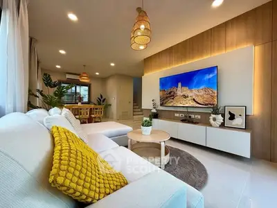 Modern living room with stylish decor and large TV, featuring cozy seating and elegant lighting.