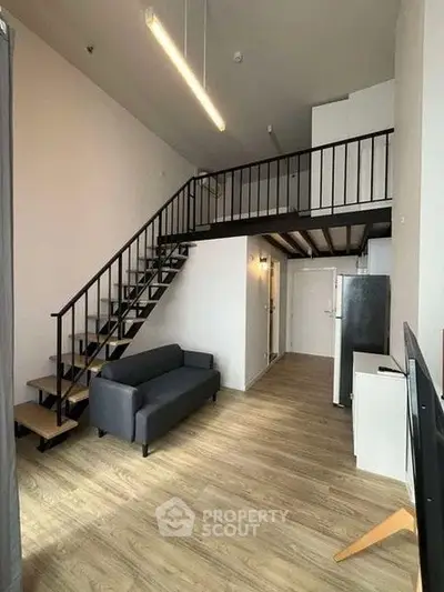 Modern loft apartment with high ceilings and mezzanine, featuring sleek staircase and stylish furnishings.