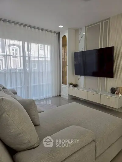 Modern living room with sleek TV setup and large windows for natural light