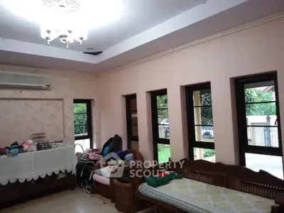 Spacious living room with large windows and garden view, featuring elegant chandelier and cozy seating area.