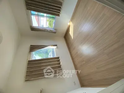 Spacious empty room with wooden flooring and large windows for natural light.