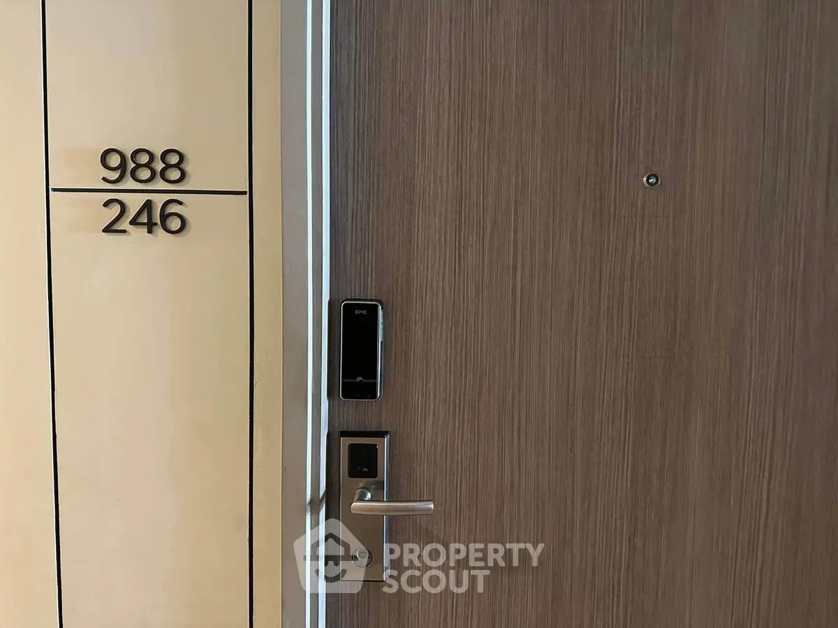 Modern apartment entrance with electronic lock and sleek wooden door design.