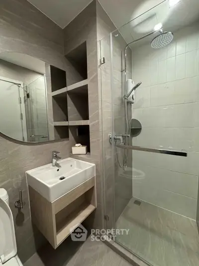 Modern bathroom with glass shower and sleek vanity in contemporary apartment.