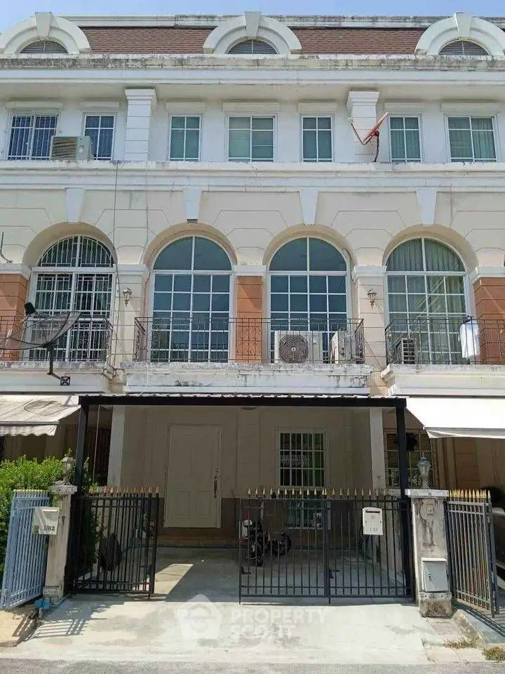 Elegant three-story townhouse with gated entrance and large windows in a desirable neighborhood.