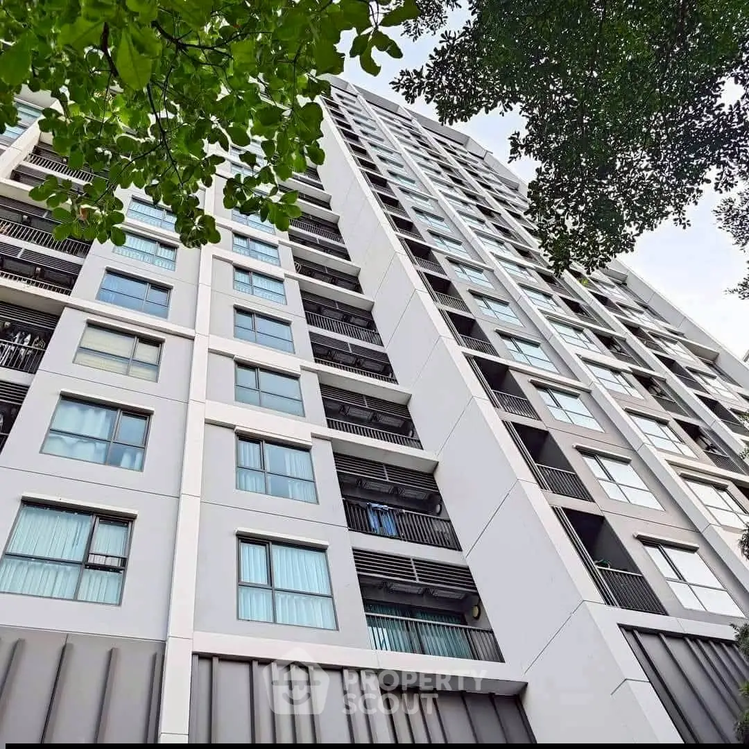 Modern high-rise building exterior with lush greenery and sleek architectural design.