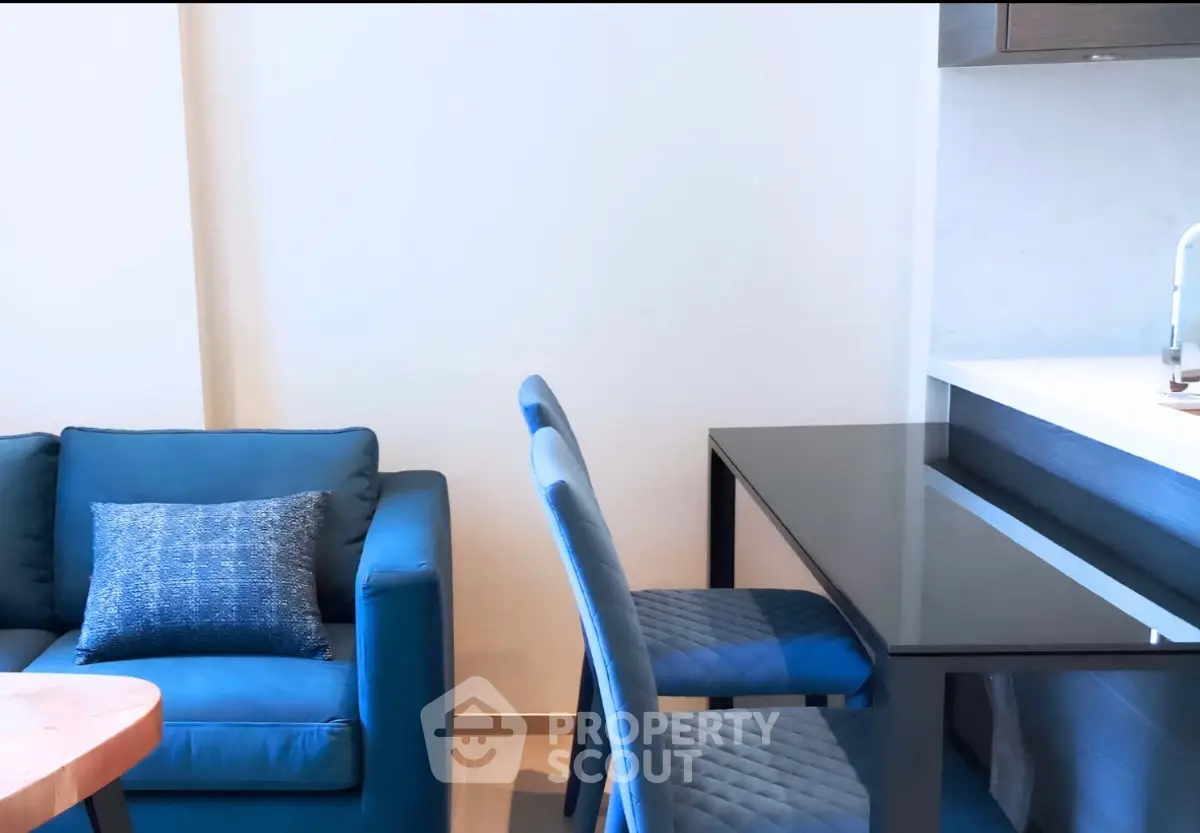 Modern living room with blue sofa and dining area, featuring sleek furniture and contemporary design.