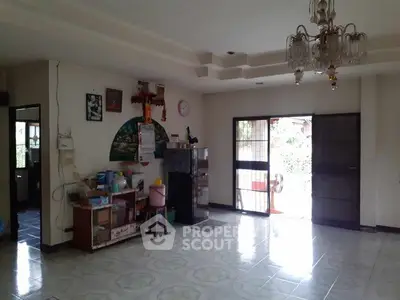 Spacious living room with chandelier and natural light, ideal for family gatherings.