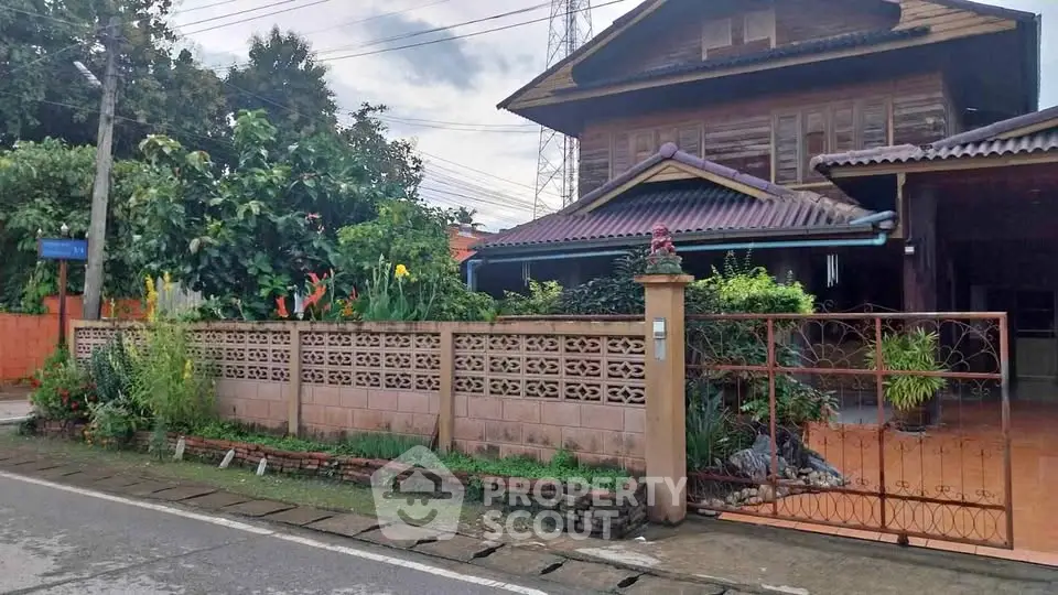 Charming traditional wooden house with lush garden and decorative fence in serene neighborhood.