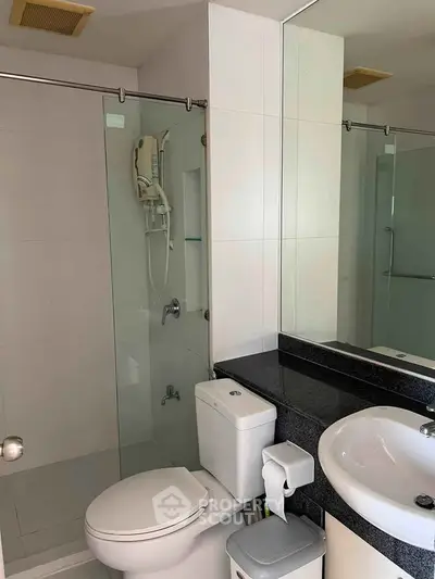 Modern bathroom with glass shower and sleek fixtures in a contemporary apartment.