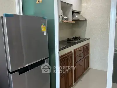 Compact kitchen with stainless steel fridge and gas stove in modern apartment