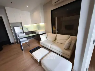 Modern open-layout living room with sleek kitchen and cozy seating area in a stylish apartment.