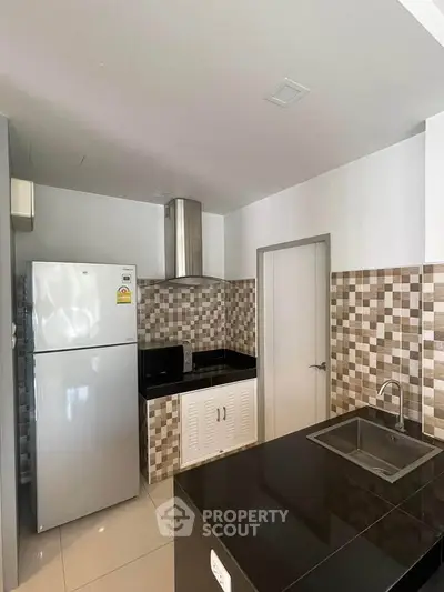 Modern kitchen with sleek black countertops and stainless steel appliances in a stylish apartment.