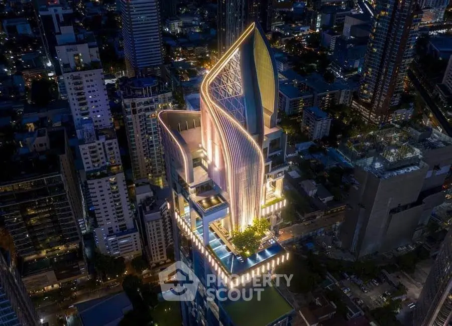 Stunning aerial view of a modern skyscraper with unique architectural design illuminated at night.