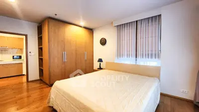 Spacious bedroom with wooden flooring and modern wardrobe in a cozy apartment.