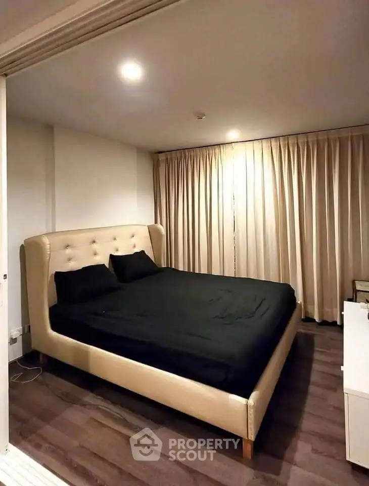 Spacious bedroom with elegant bed and floor-to-ceiling curtains in modern apartment.