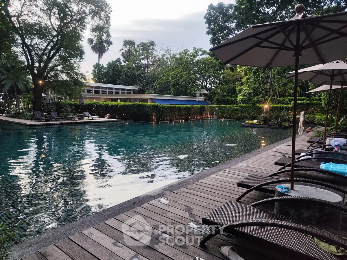 Luxurious outdoor pool area with sun loungers and lush greenery, perfect for relaxation and leisure.