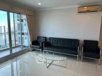 Spacious living room with modern furniture and city view balcony in high-rise apartment.
