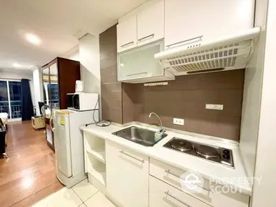 Modern kitchen with sleek cabinetry and electric stove in open-plan apartment