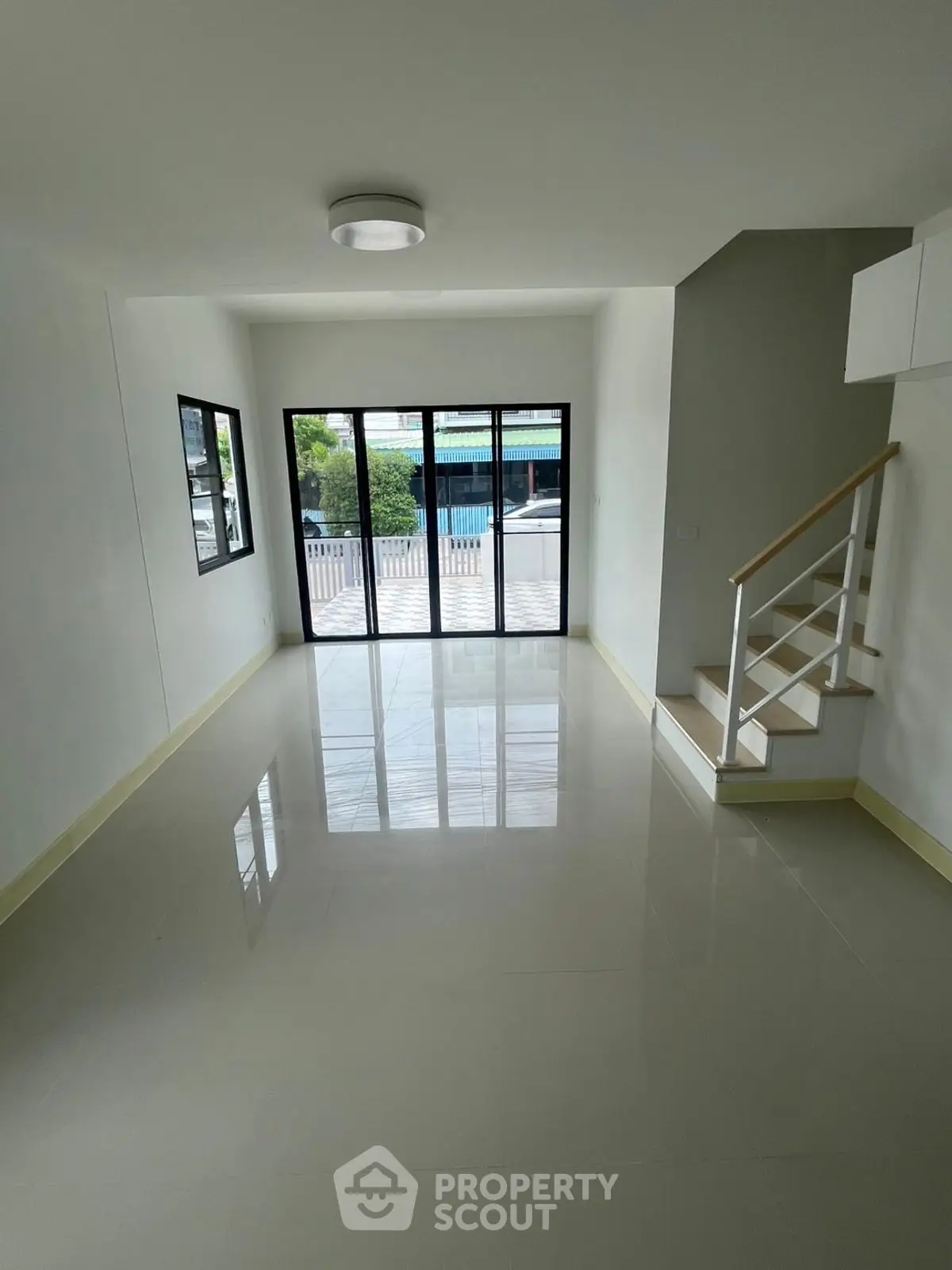 Spacious modern living room with large windows and sleek staircase