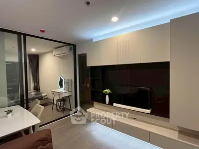 Modern living room with sleek furniture and glass partition leading to bedroom