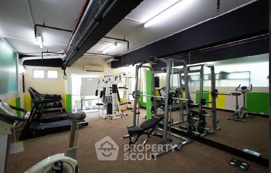 Spacious gym with modern equipment and mirrored walls in a residential building.