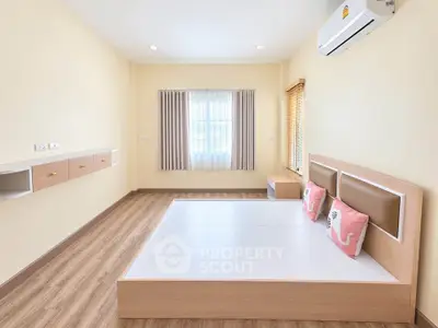 Spacious bedroom with modern design and natural light, featuring a stylish bed and air conditioning.