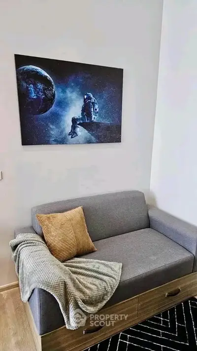 Modern living room with stylish gray sofa and space-themed wall art, perfect for cozy relaxation.