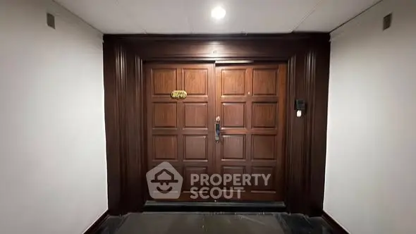 Elegant wooden entrance door with intricate panel design in a well-lit hallway.