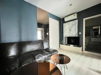 Modern living room with sleek black sofa and wall-mounted TV in stylish apartment.