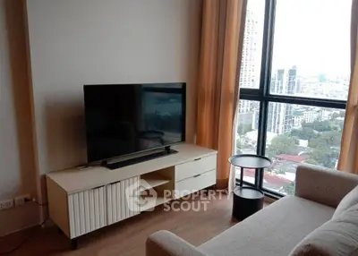 Modern living room with large window and city view, featuring a sleek TV setup and cozy seating.