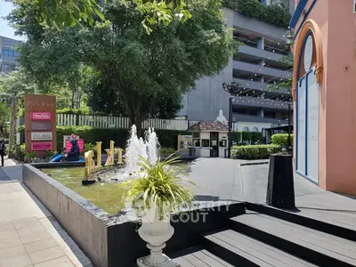 Charming outdoor plaza with fountain and lush greenery, ideal for retail or dining businesses.
