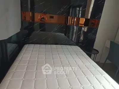 Modern bedroom with marble accent wall and comfortable mattress in stylish apartment.