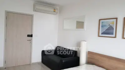 Modern bedroom with air conditioning, black sofa, and stylish wall art.